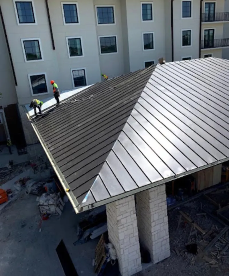 Crew installing standing seam metal roof panels on a commercial project in Malibu